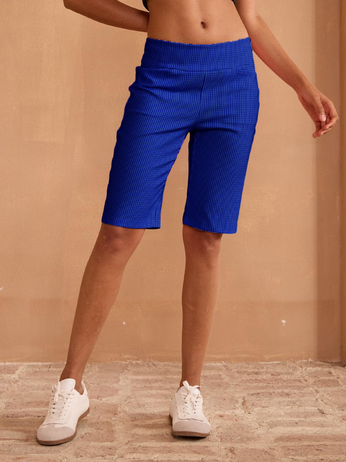 Woman wearing blue high-waisted athletic golf shorts and white sneakers.
