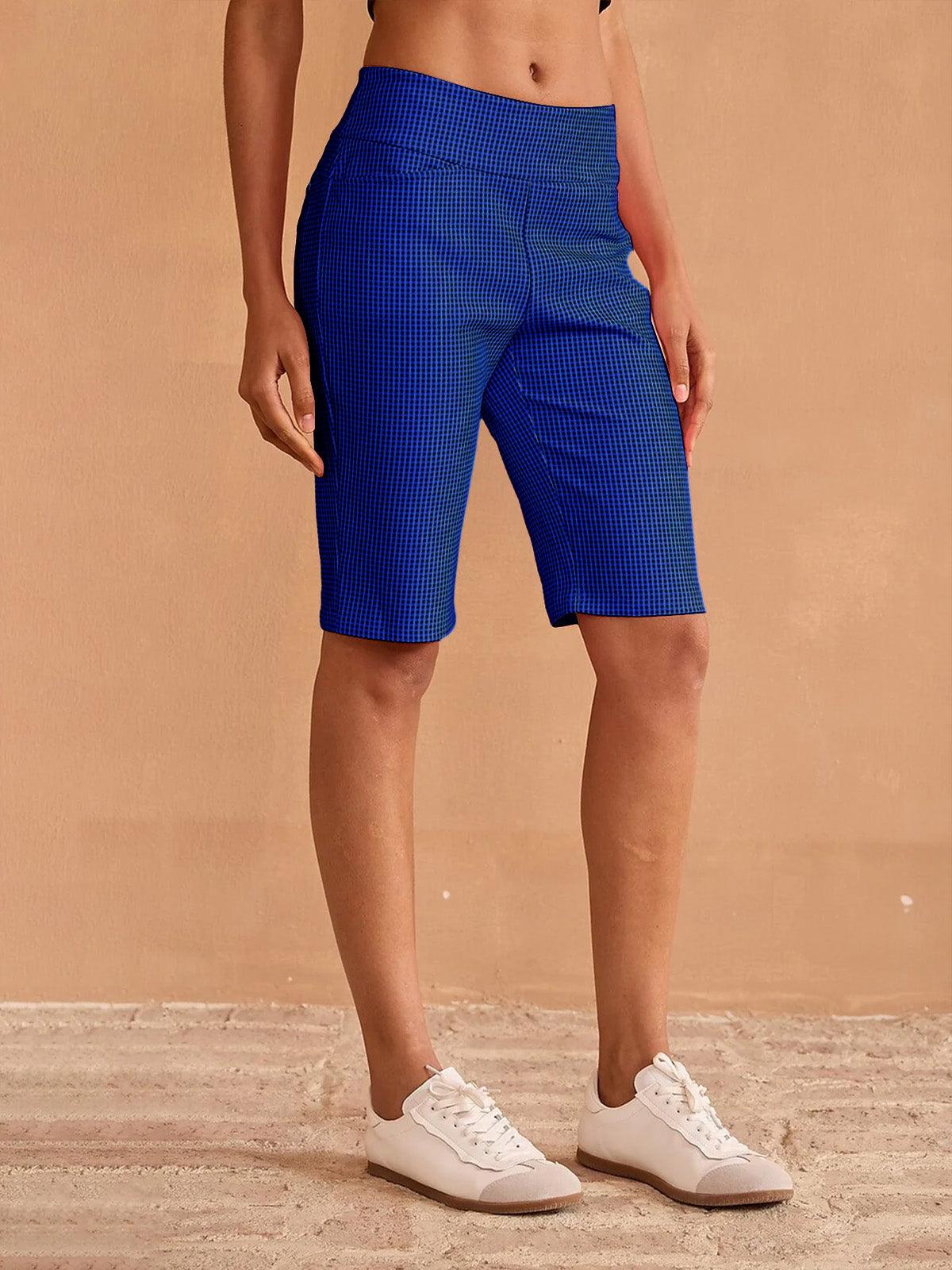 Woman wearing blue patterned performance golf shorts and white sneakers.
