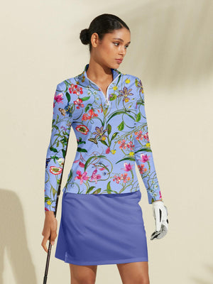 Woman wearing a light blue floral print long sleeve golf shirt and matching blue golf skirt.