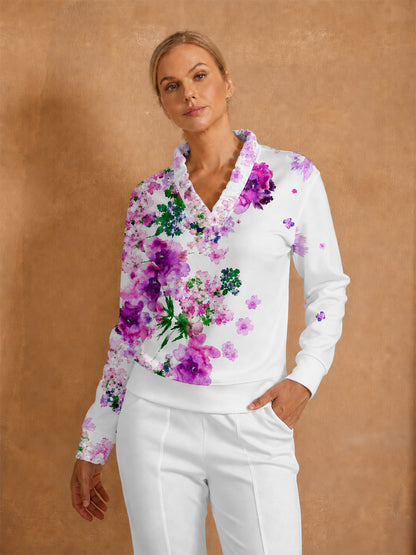 Woman wearing a white floral print long sleeve golf pullover and white performance trousers