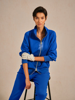 Woman wearing a blue performance golf tracksuit and a white golf glove.