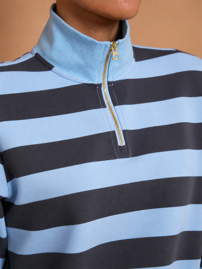Close-up of a women's blue and navy striped quarter-zip golf pullover with gold zipper.
