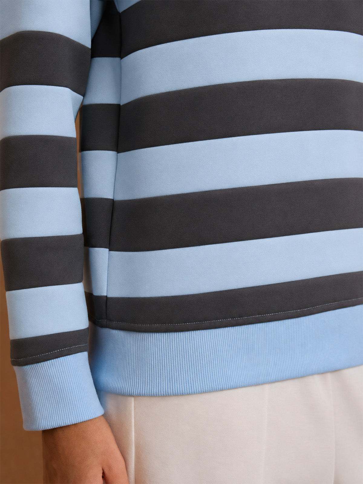 Women's light blue and navy striped long sleeve golf pullover with ribbed hem.