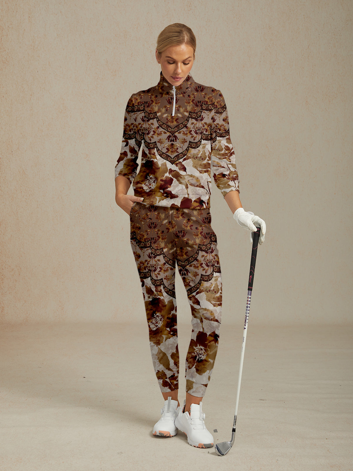 Woman wearing a patterned floral golf tracksuit with a quarter-zip top and matching pants.