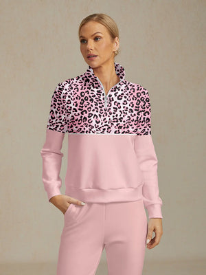 Woman wearing a pink and leopard print quarter-zip golf pullover and matching pink pants.