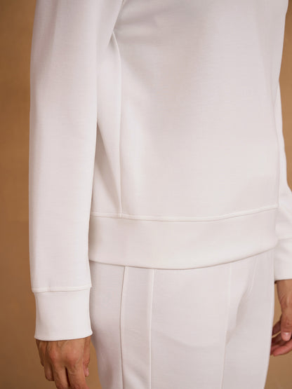 Women's white performance golf sweatshirt and matching trousers set.