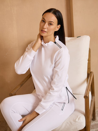 Woman wearing a white long-sleeve performance golf sweatshirt and matching athletic pants.