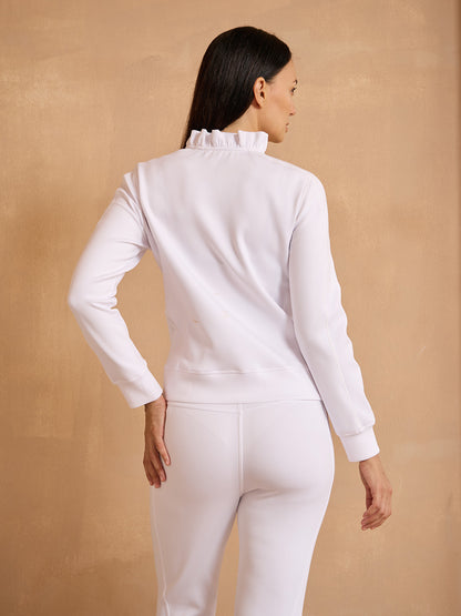 Woman wearing white long-sleeve performance golf top and matching trousers.