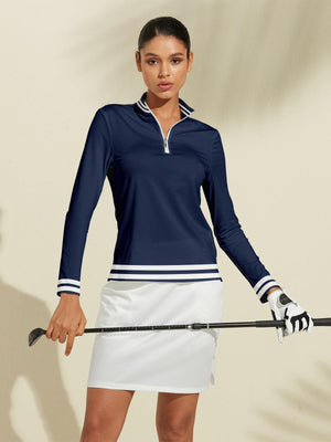 Woman wearing a navy blue long sleeve quarter-zip golf top and a white golf skirt.