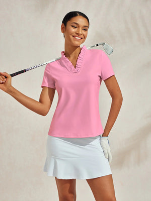 Smiling woman wearing a pink ruffled polo shirt and white golf skort holding a golf club.