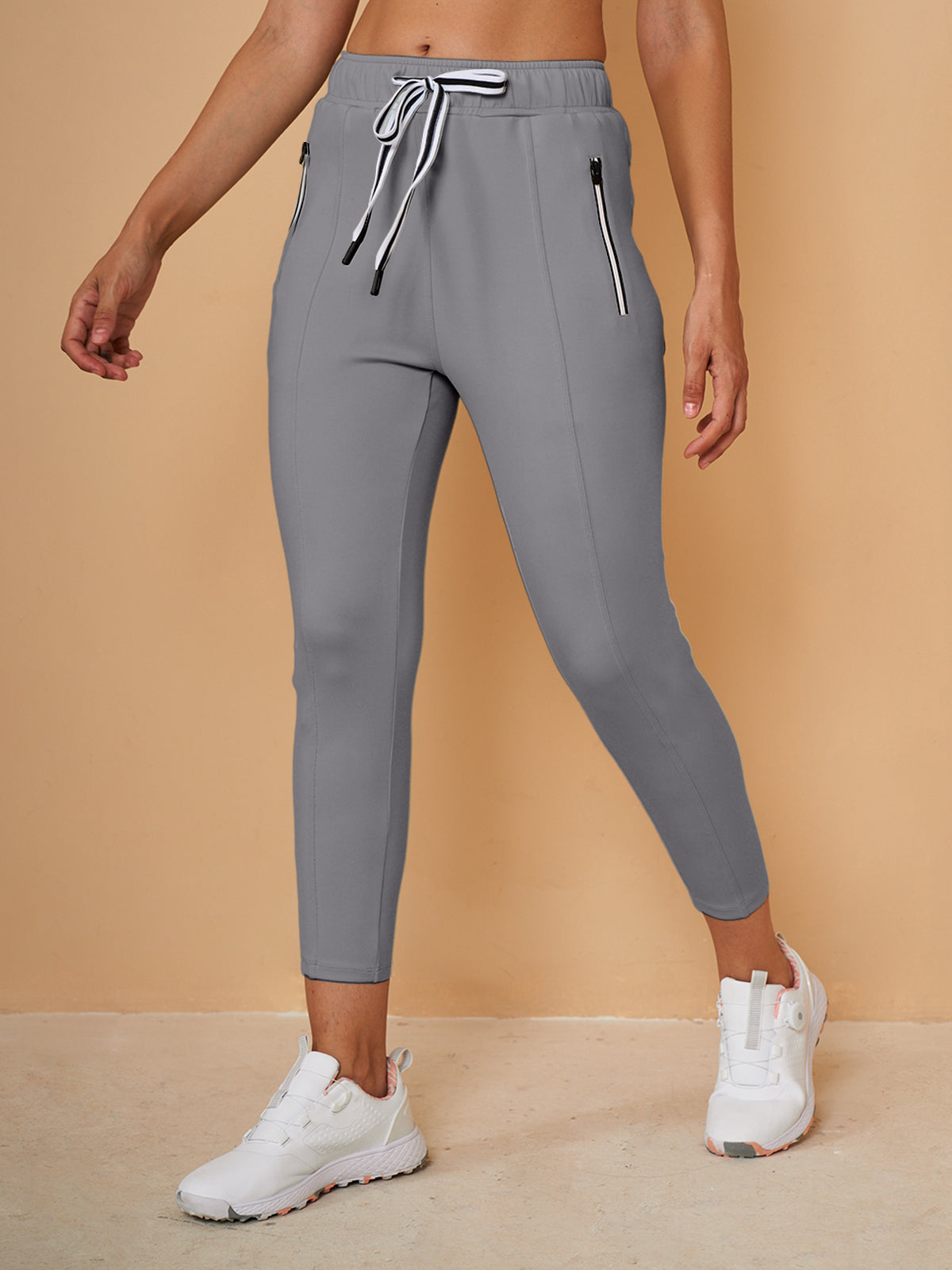 Woman wearing grey cropped golf pants with drawstring waist and white sneakers
