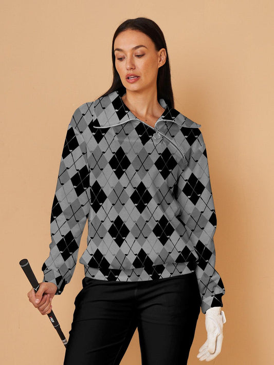 Woman wearing a grey and black argyle print quarter-zip golf pullover holding a golf club.