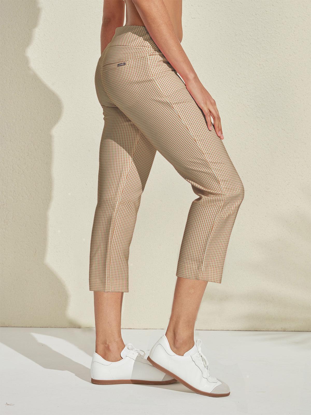 Woman wearing tan gingham pattern women's golf cropped trousers and white sneakers.
