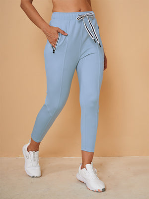 Women's light blue performance golf capris with drawstring waist and side pockets.