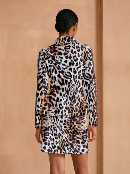 Woman wearing a leopard print long sleeve top and matching mini skirt set.