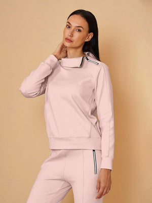 Woman wearing a light pink performance golf sweatshirt and matching athletic pants.
