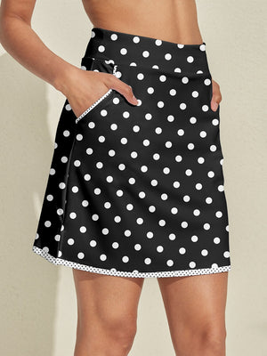 Woman wearing a black polka dot golf skort with functional side pockets.