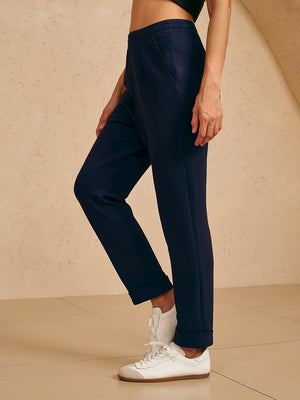 Woman wearing navy blue performance golf trousers and white sneakers