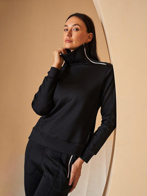 Woman wearing a black performance long-sleeve golf quarter-zip pullover and matching pants.