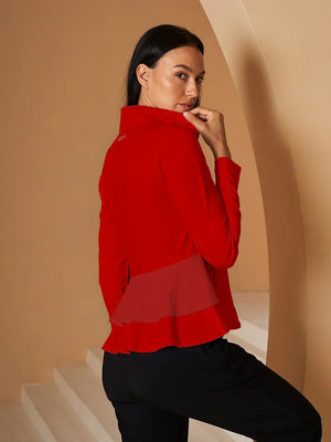 Woman wearing a red long-sleeve performance golf top and black trousers.