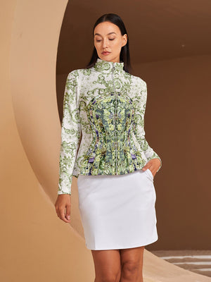 Woman wearing a floral print long-sleeve golf polo and white golf skirt.
