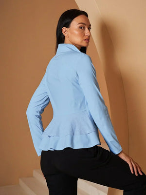 Woman wearing a light blue long-sleeve performance golf top with a ruffled peplum hem.