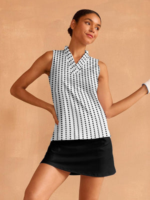 Woman wearing a white sleeveless polo with black polka dots and a black golf skirt.